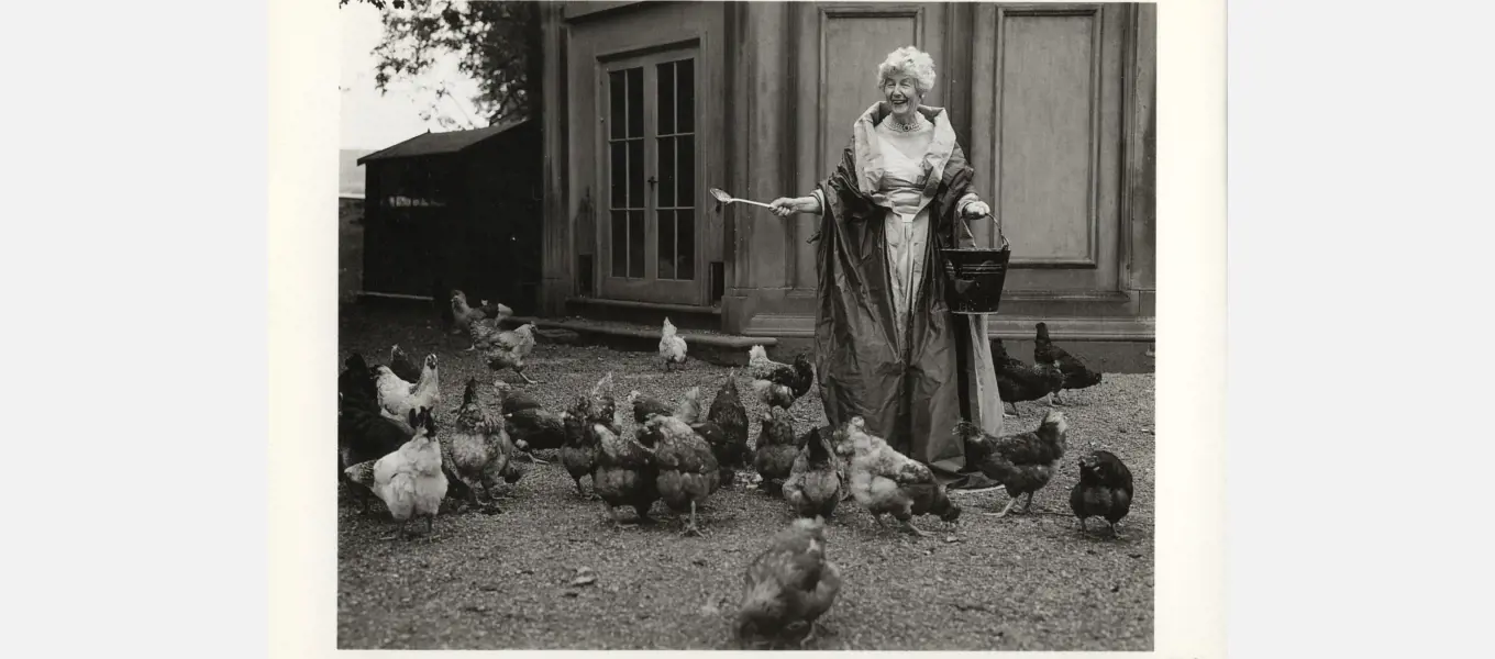 Duchess Deborah feeding her chickens outside the game larder while wearing vintage couture (c) Bruce Weber